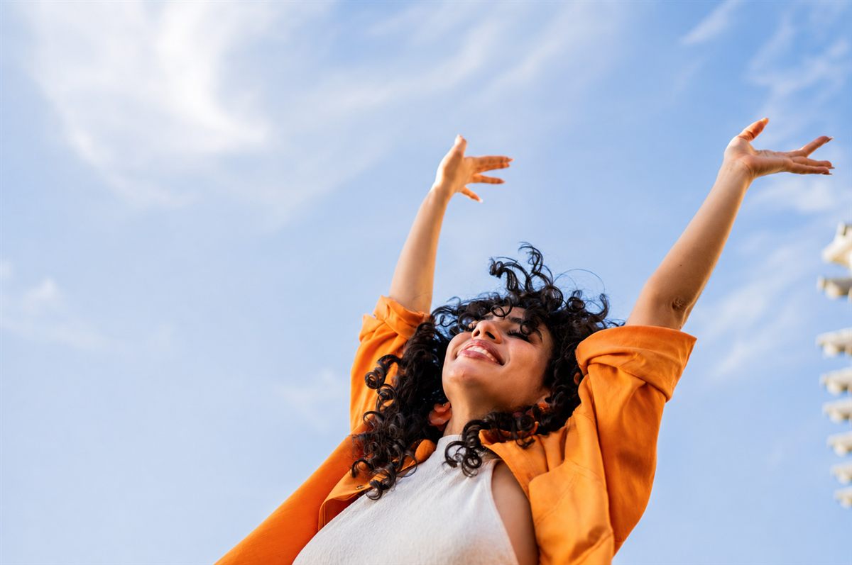 A woman with arms raised to an open sky, a feeling of relief and calm