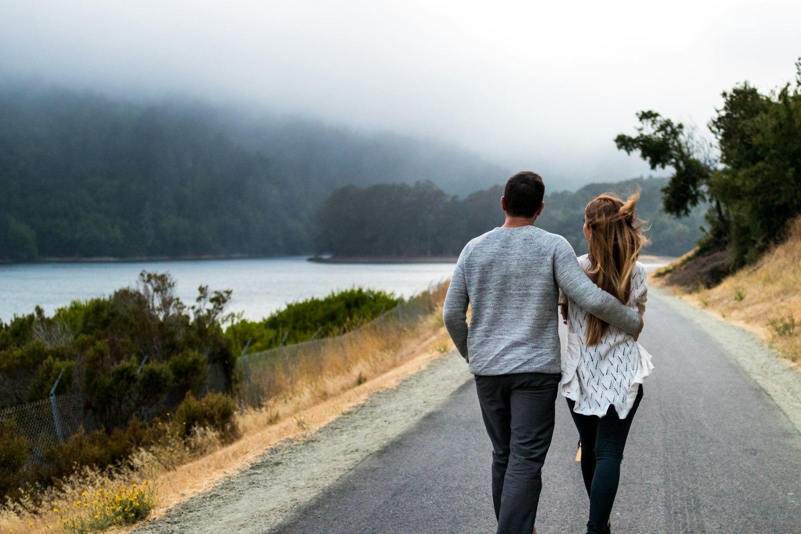 A couple walking together along a quiet road by the water