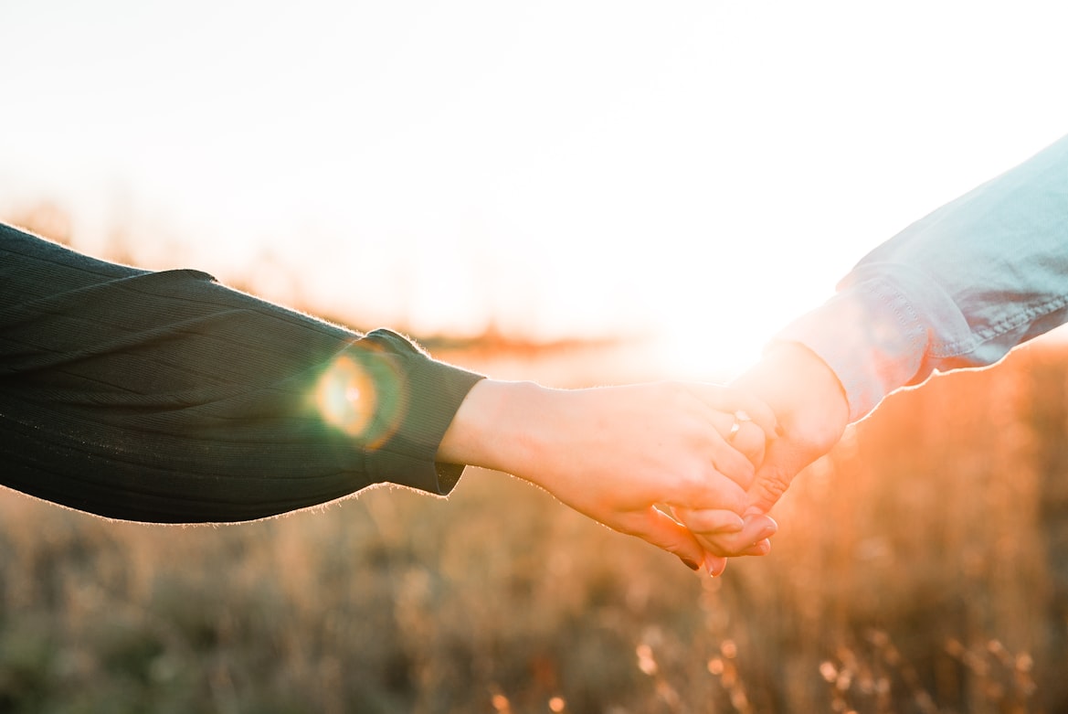Two people holding hands in warm evening light â steady support after a car accident